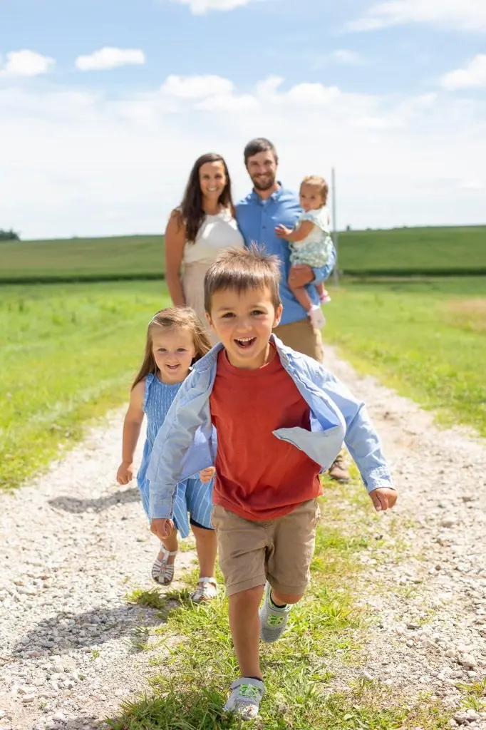 Blake and Alicia Andera with their children walking down a gravel farm lane in Iowa